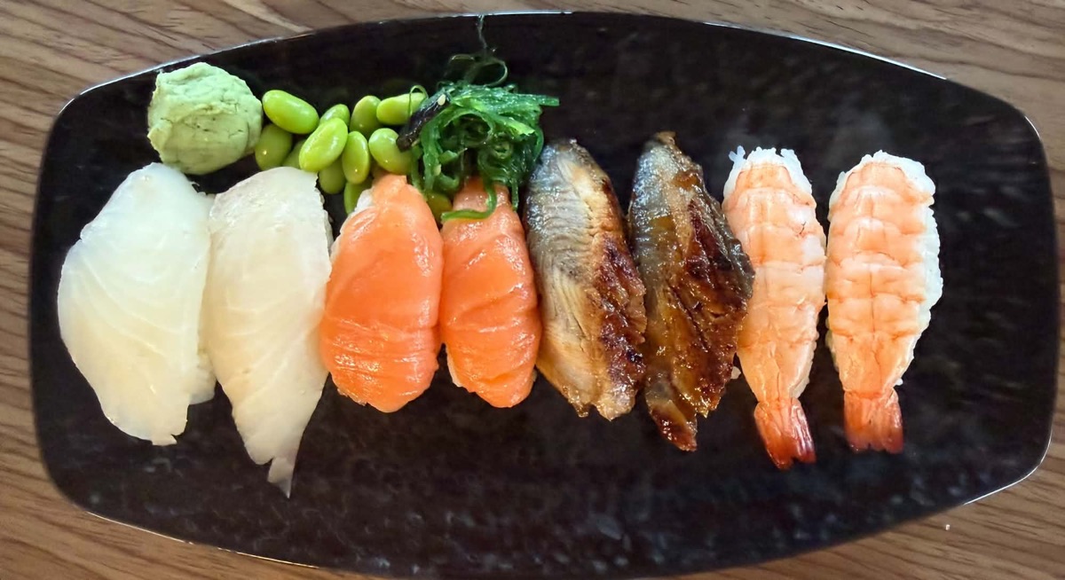 Nigiri med vit fisk, lax, ål och räkor på ett svart fat